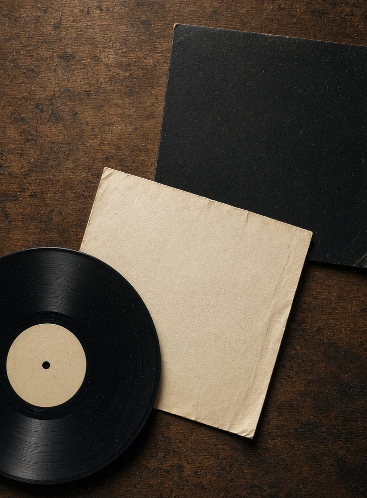 Black vinyl record and cream paper sleeve on a wooden table